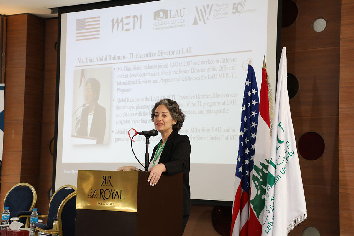A photo of a woman standing behind a podium and speaking. 
