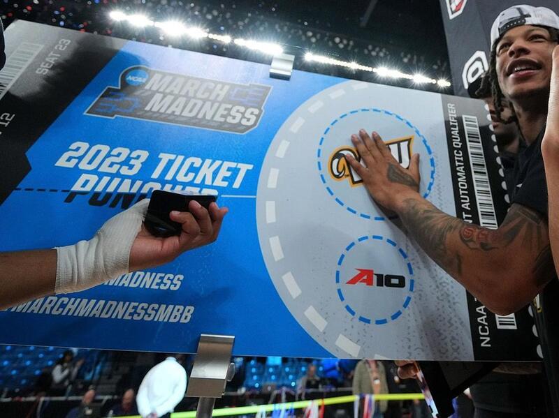 A man holding a giant ticket to a basket ball game 