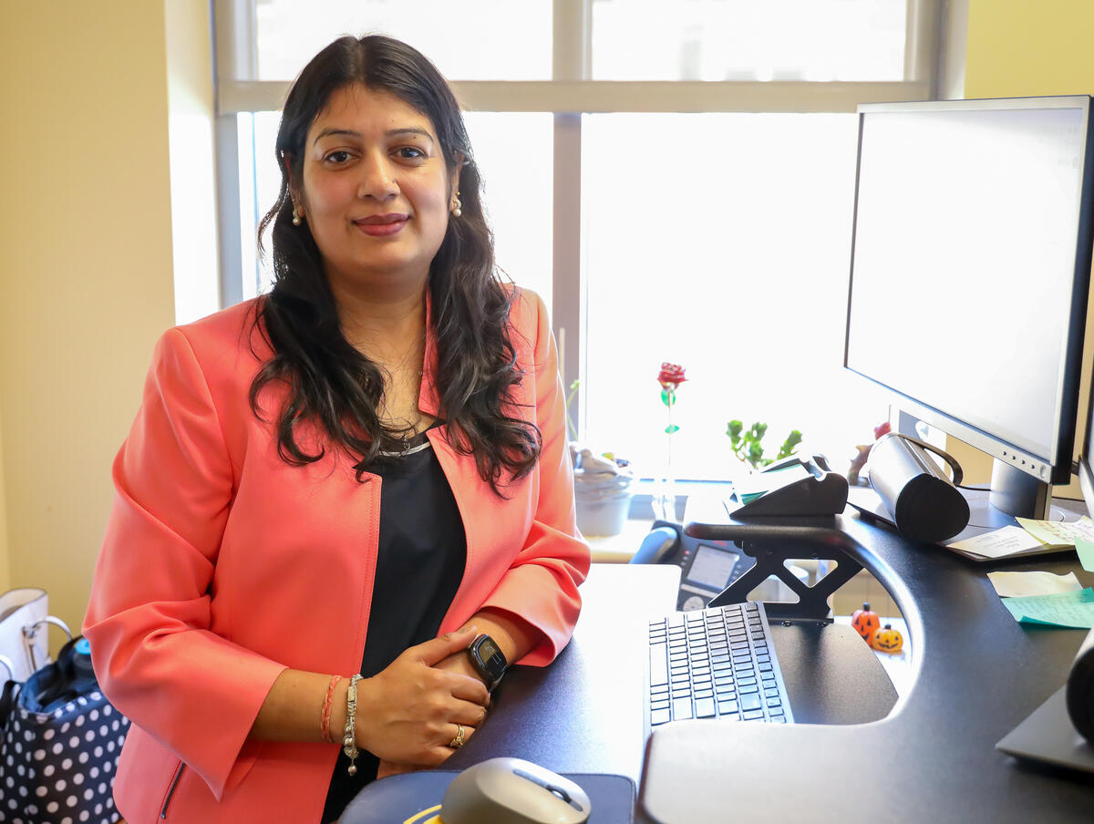 A photo of a woman standing at a desk with a computer on it. 
