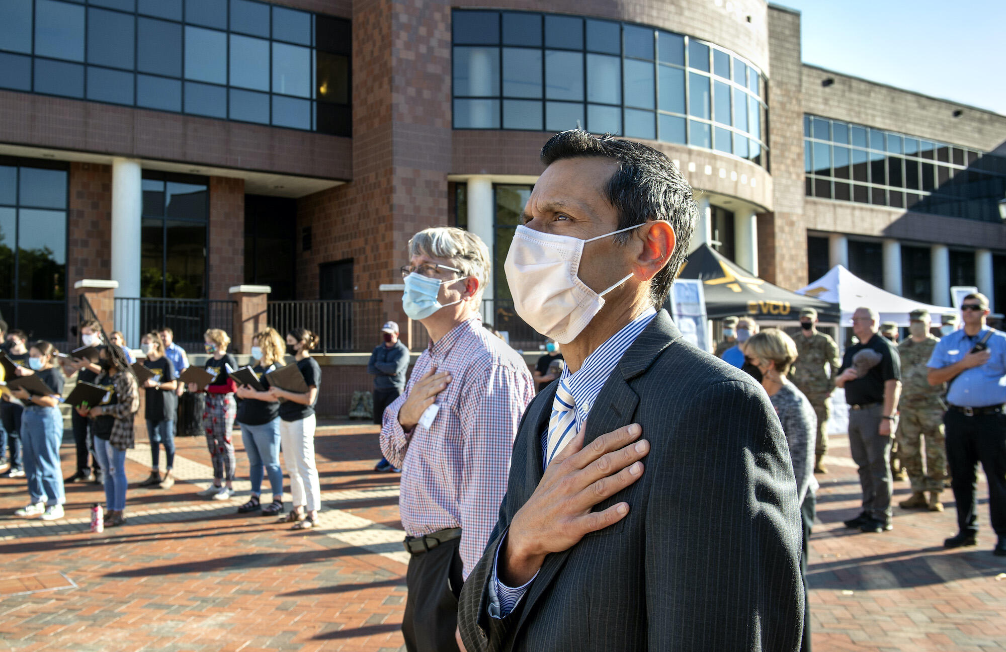 VCU President Michael Rao stands with his hand over his heart at a 9/11 anniversary event.