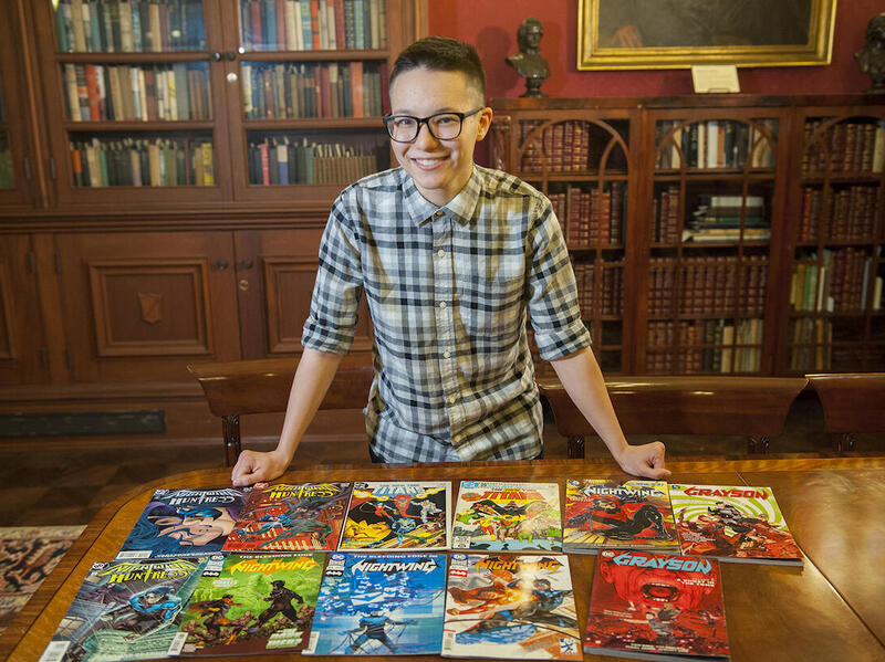 Thea Cheuk standing at a table with comic books spread out in front.