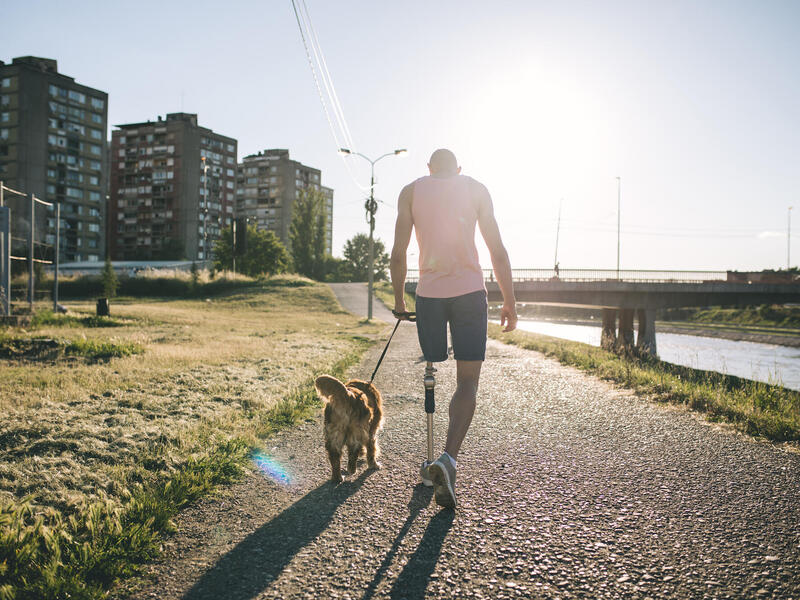 man with prosthetic leg walking his dog
