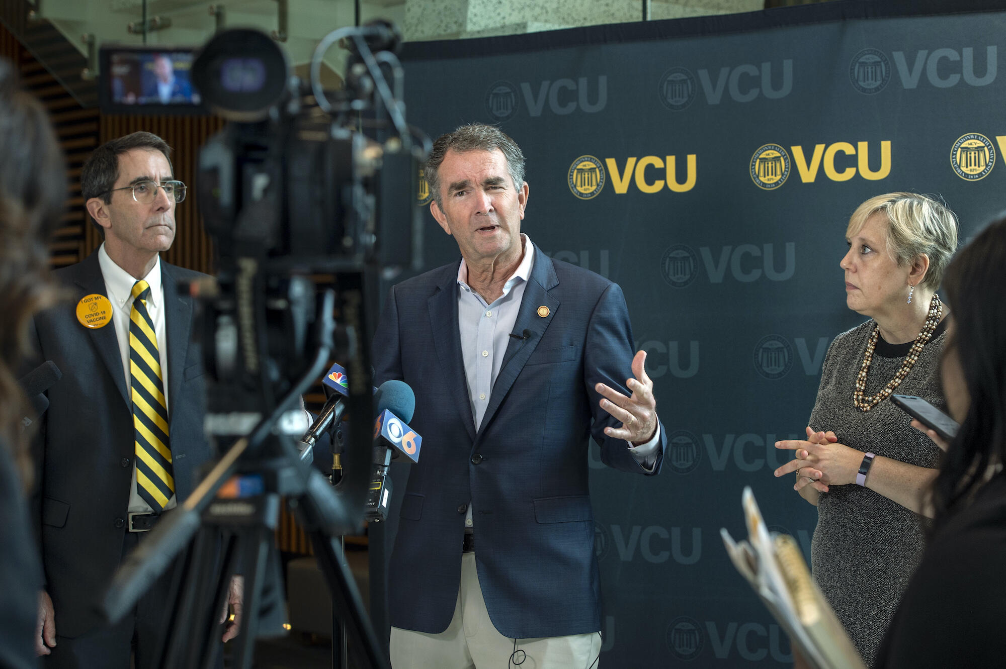 Virginia Gov. Ralph Northam, M.D., (center) addresses reporters Thursday as Art Kellermann, M.D., (left) senior vice president for VCU Health Sciences and CEO of VCU Health System, and Susan Parish, Ph.D., (right) dean of VCU's College of Health Professions, look on during the governor's visit to the college's building. 