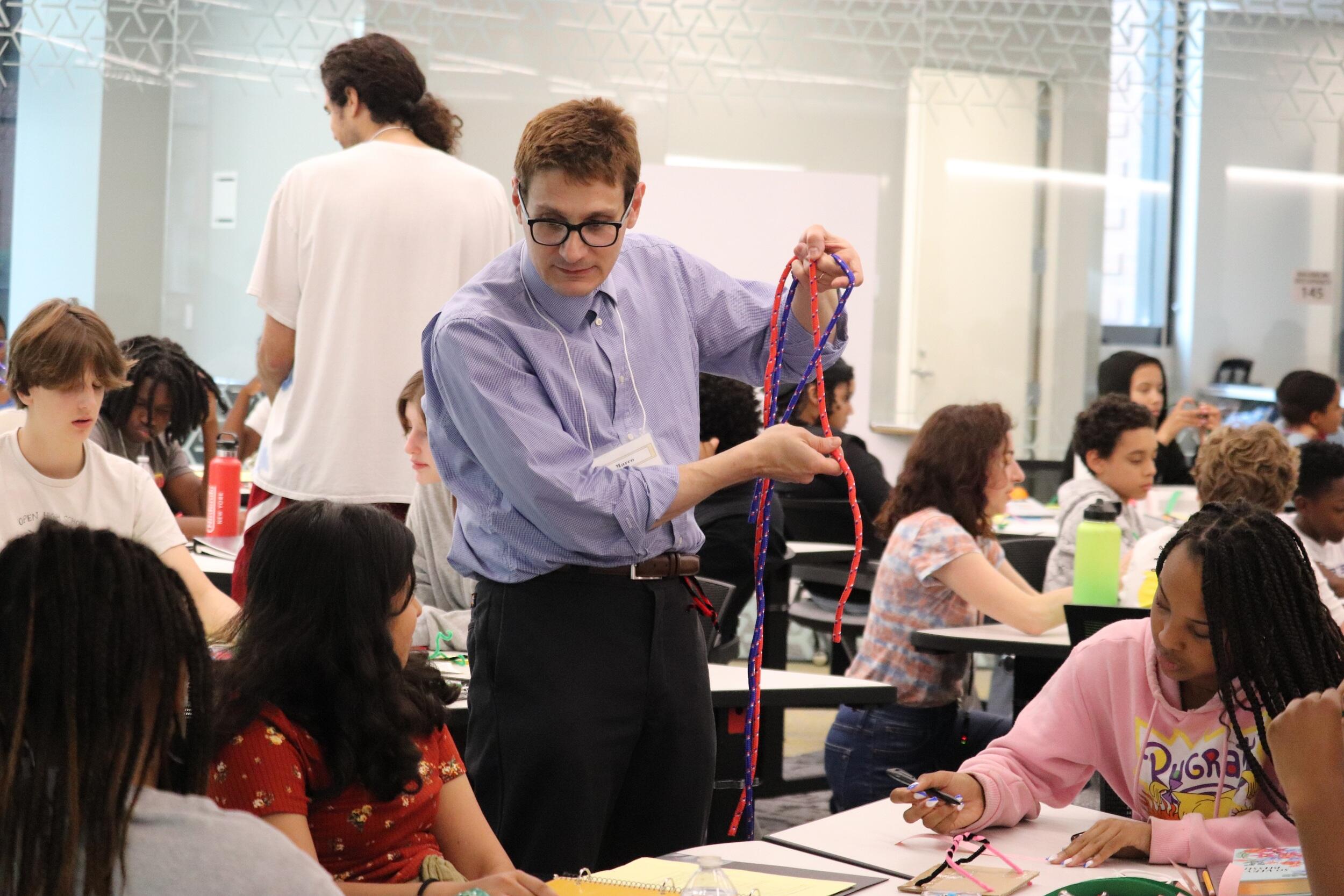 A photo of a man standing next to teenagers at a table