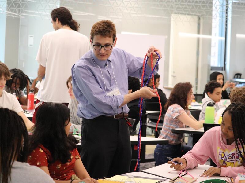 A photo of a man standing next to teenagers at a table