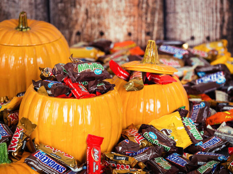 A photo of fake pumpkins filled with pieces of chocolate candy. 
