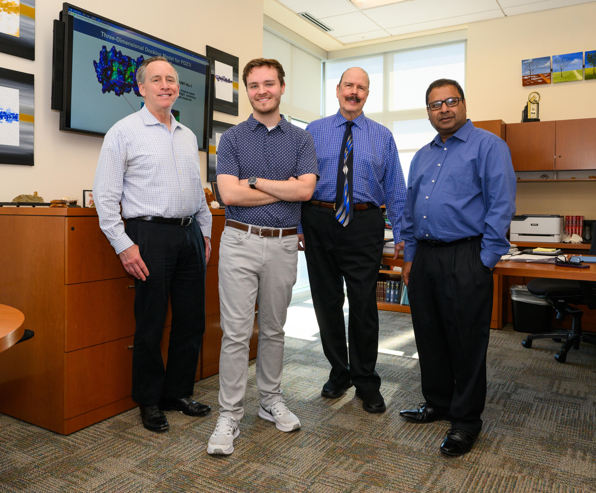 A group photo of four men standing in a room. 