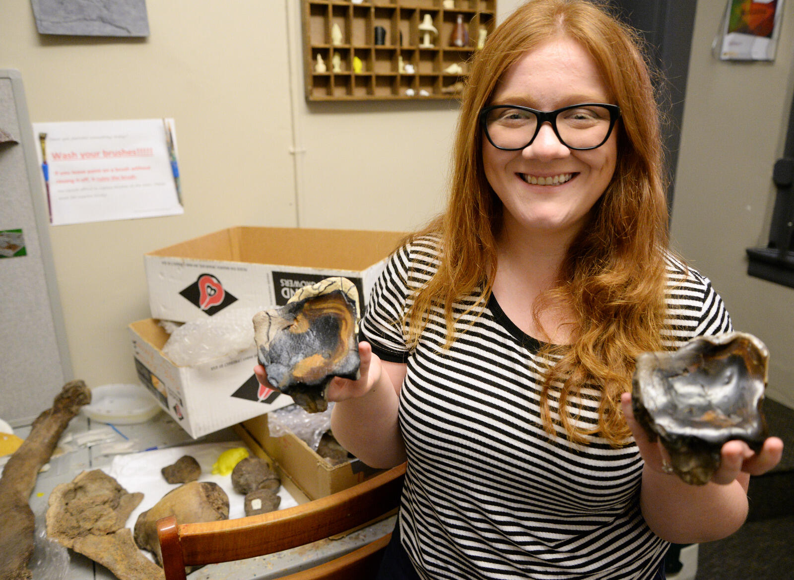 Kristen Egan, a senior anthropology major who interned in the Virtual Curation Laboratory, shows off a mastodon tooth fossil and a 3-D-printed replica that she painted.
