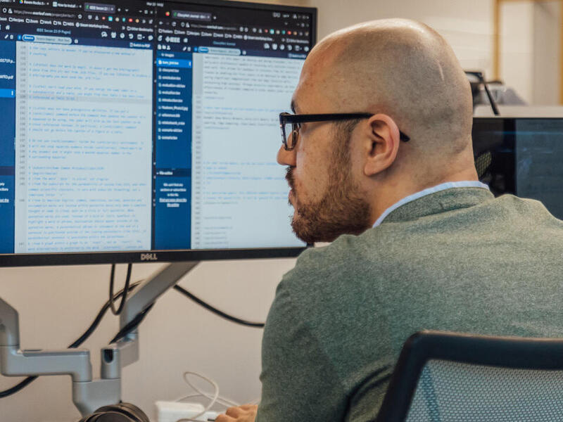 A man in glasses looks at a computer screen.