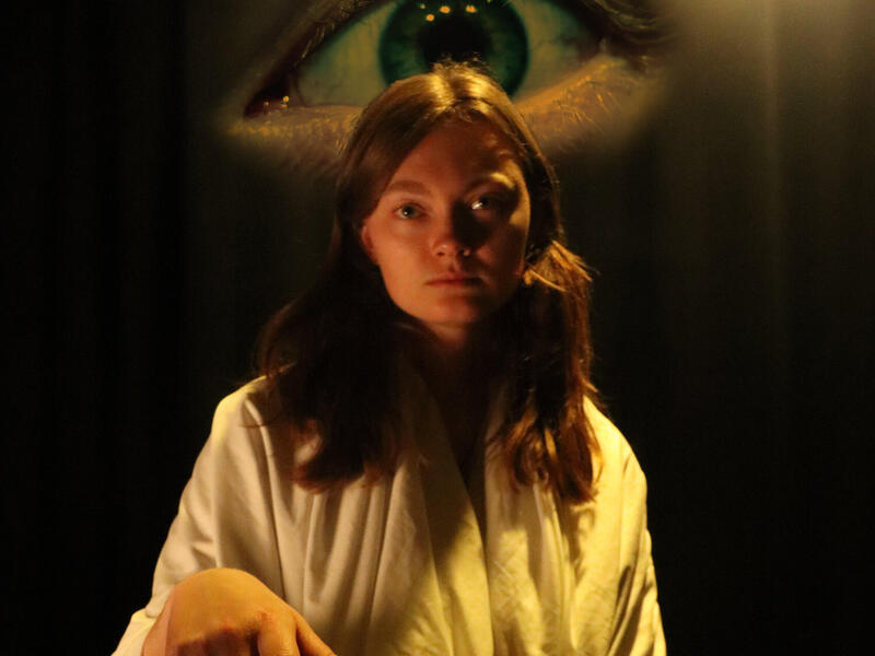 A photo of a woman with a large eye behind her