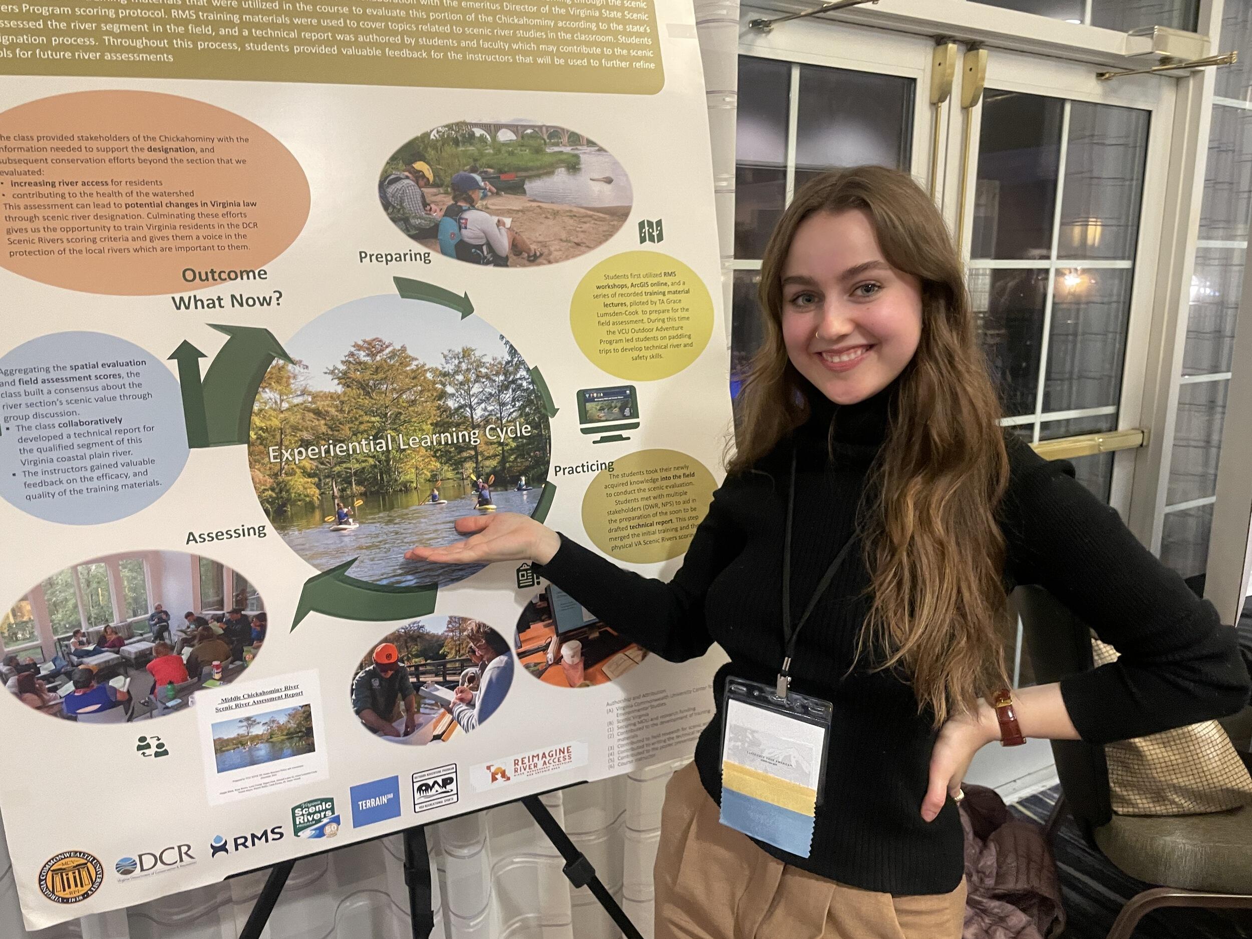 A woman standing to the right of a poster with an infographic on it. 