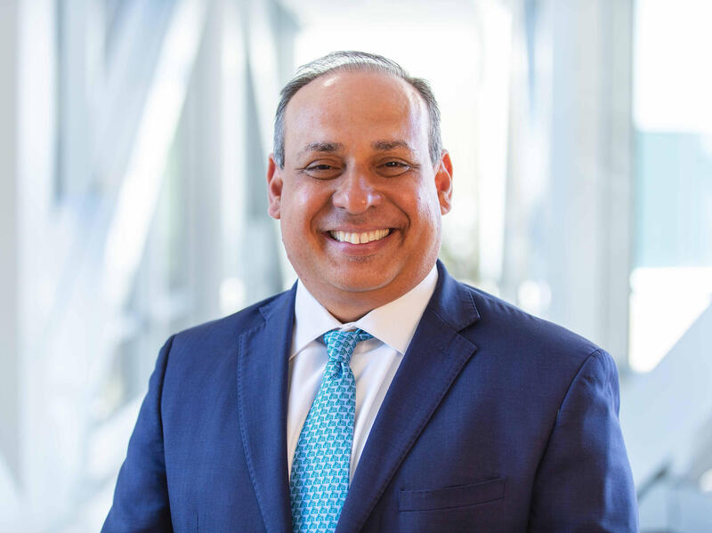 A photo of a man smiling from the chest up. 