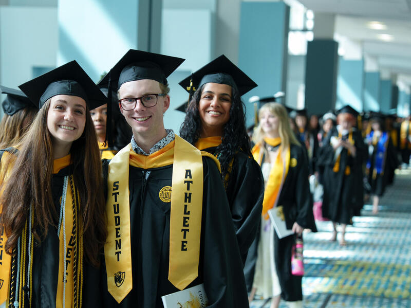 A long row of men and women in caps and gowns.