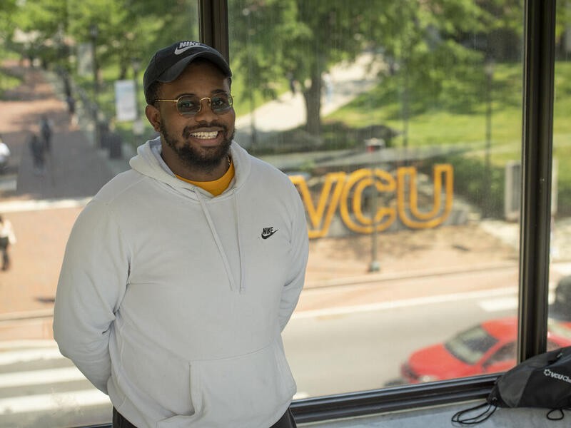 Trevohn Robinson leaning against a window facing the street. 