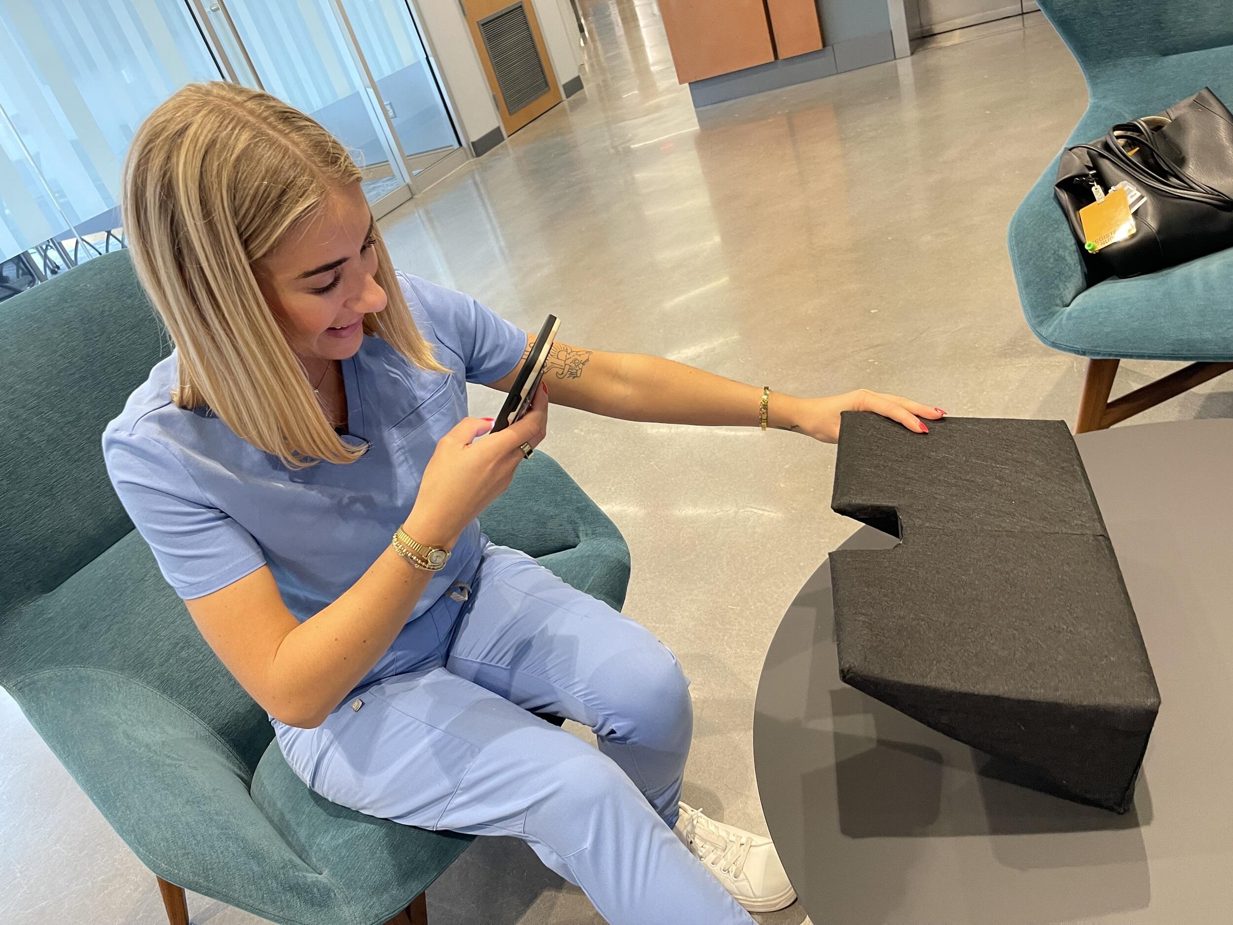 A photo of a woman taking a picture of an object with her iphone. 