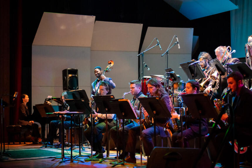 A photo of a jazz orhestra on a stage playing music. 