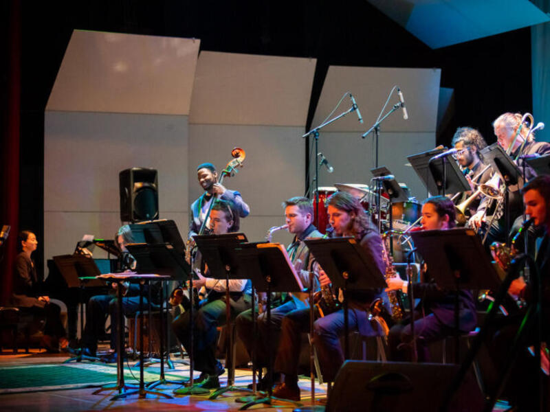 A photo of a jazz orhestra on a stage playing music. 