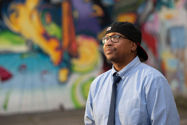 Marc Cheatham, wearing a backwards baseball cap, standing in front of a colorful mural in Richmond.