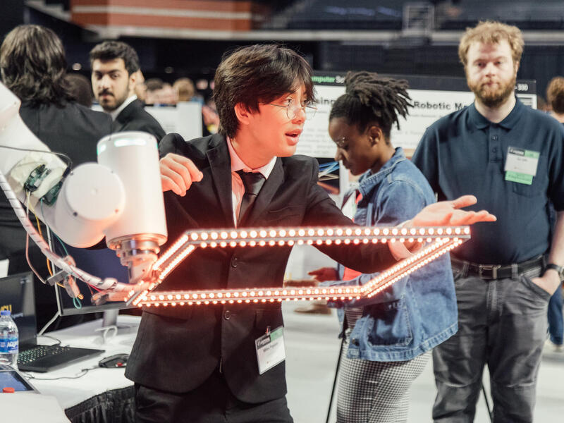 A man standing in front of a robotic arm with a lit up rectangle