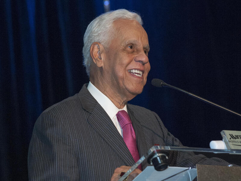L. Douglas Wilder standing at a podium speaking into a microphone 