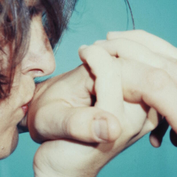 Cover of The Spinanes reissue of its first album, "Manos." The cover image is a woman holding and kissing someone's hand.