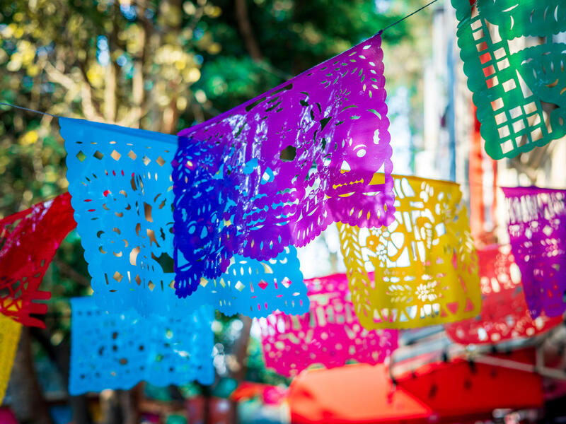 Pieces of colorful paper with designs cut out of them hanging on string 