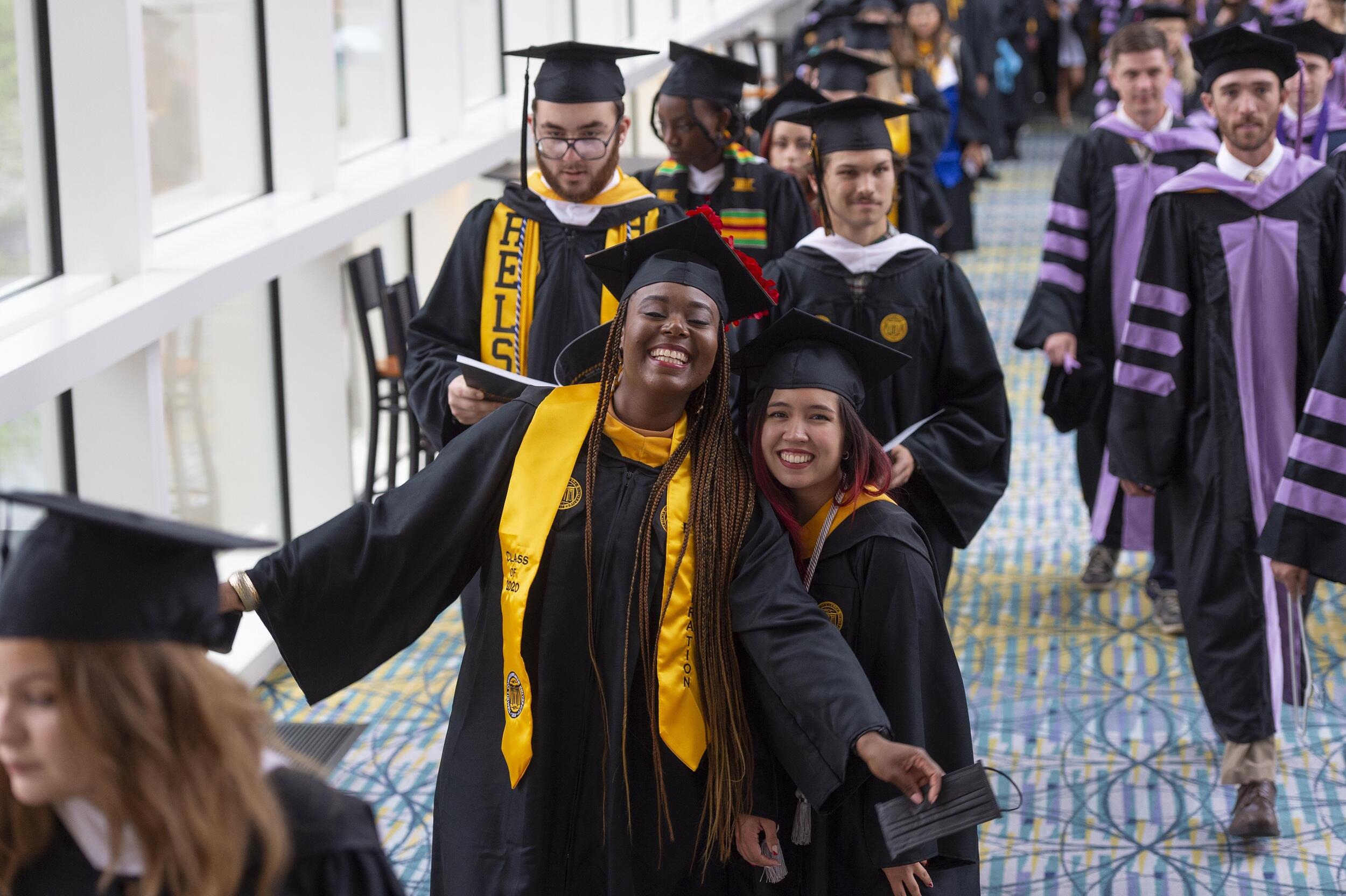 Students in cap and gowns walking down a hallway