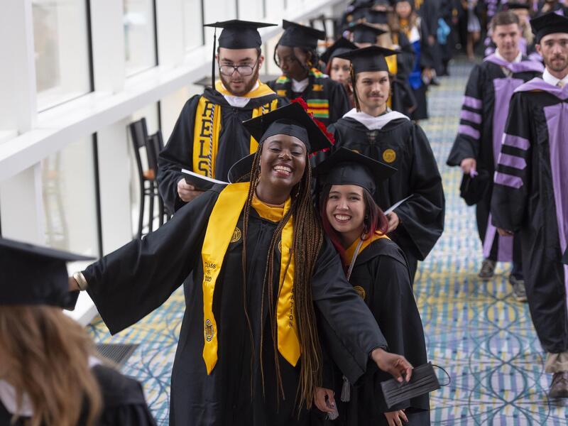 Students in cap and gowns walking down a hallway