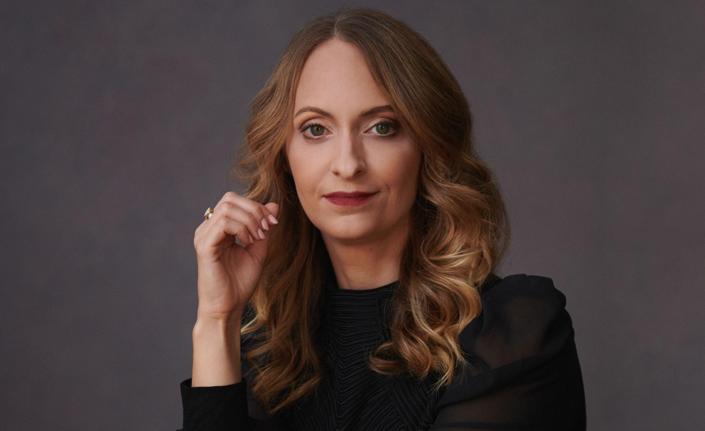 A portrait of a woman wearing a black turtle neck. 