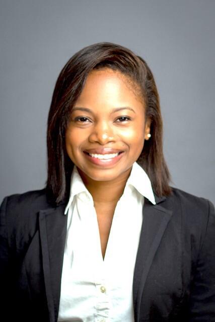 A woman wearing a white button up shirt and black sports coat smiling 