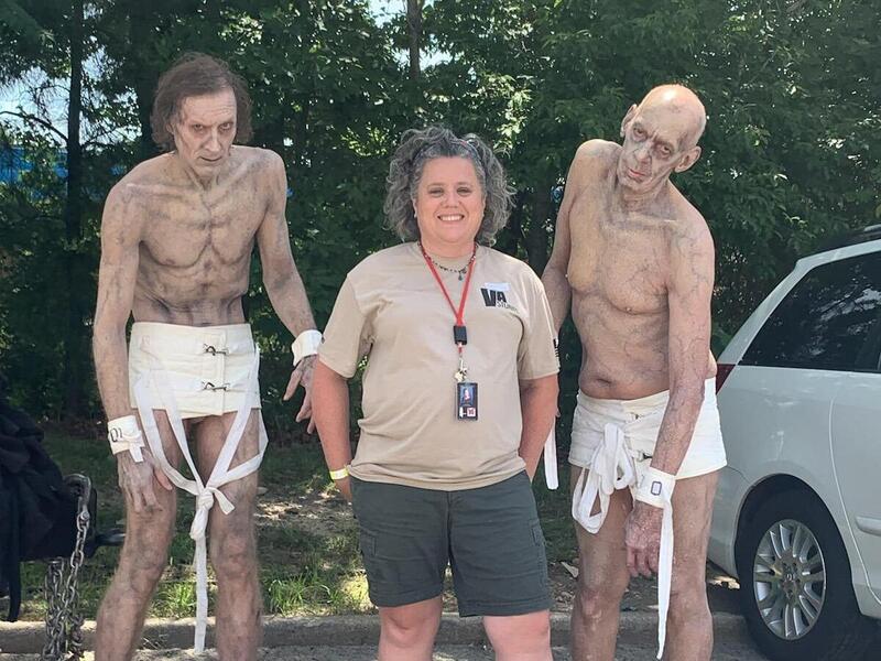 A woman standing between two men dressed as zombies 