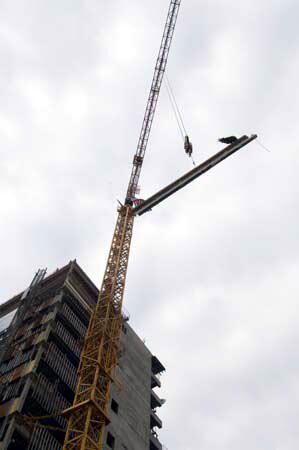 During the ceremony, a crane lifts the steel beam to the top of the 15-story Critical Care Hospital building. A tree and the American flag are attached to the beam. Photo by Allen Jones, VCU Creative Services
