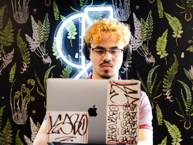 A man in headphones looks at a laptop screen.