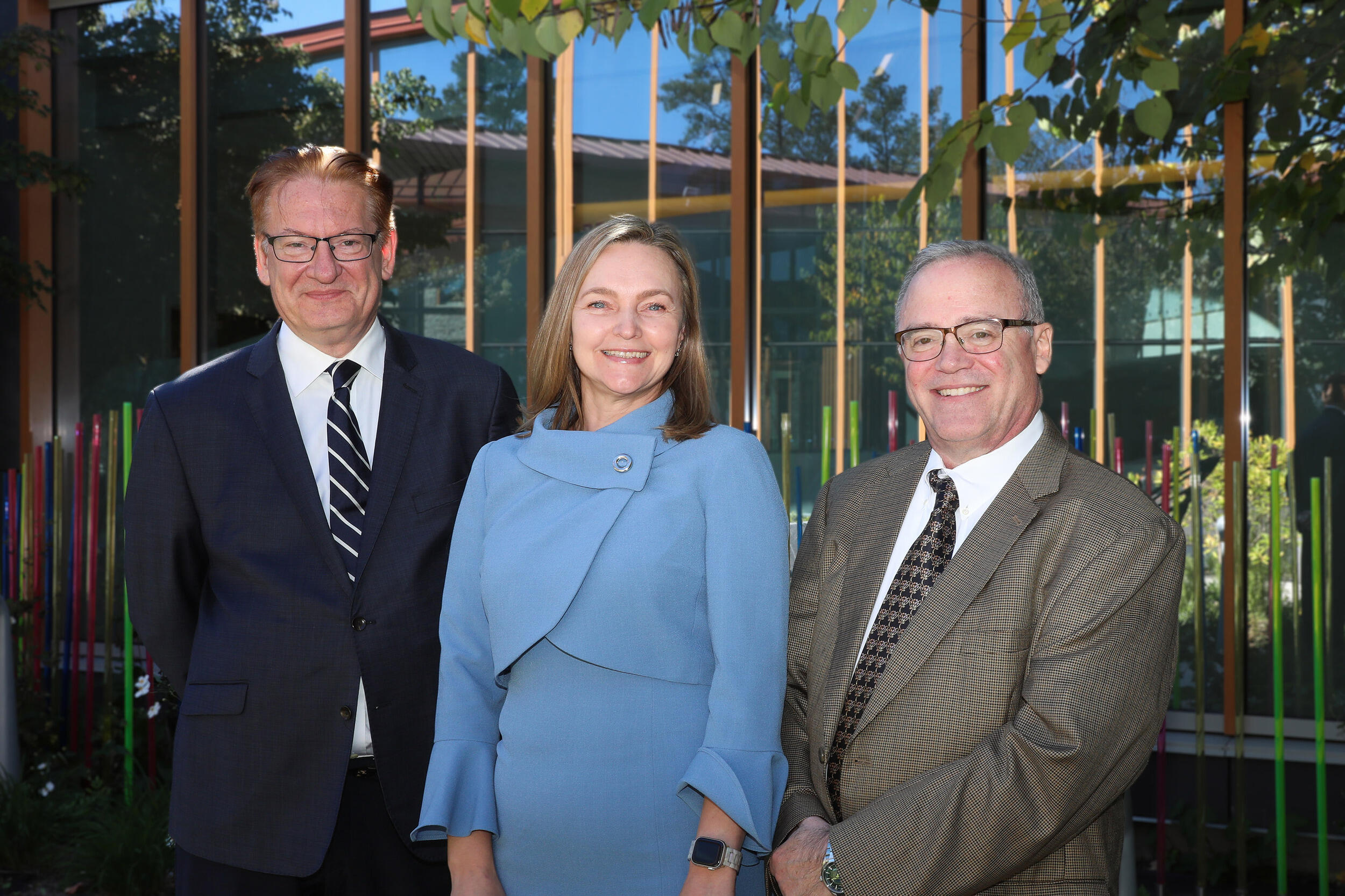A group photo of two men standing on either side of a woman. 