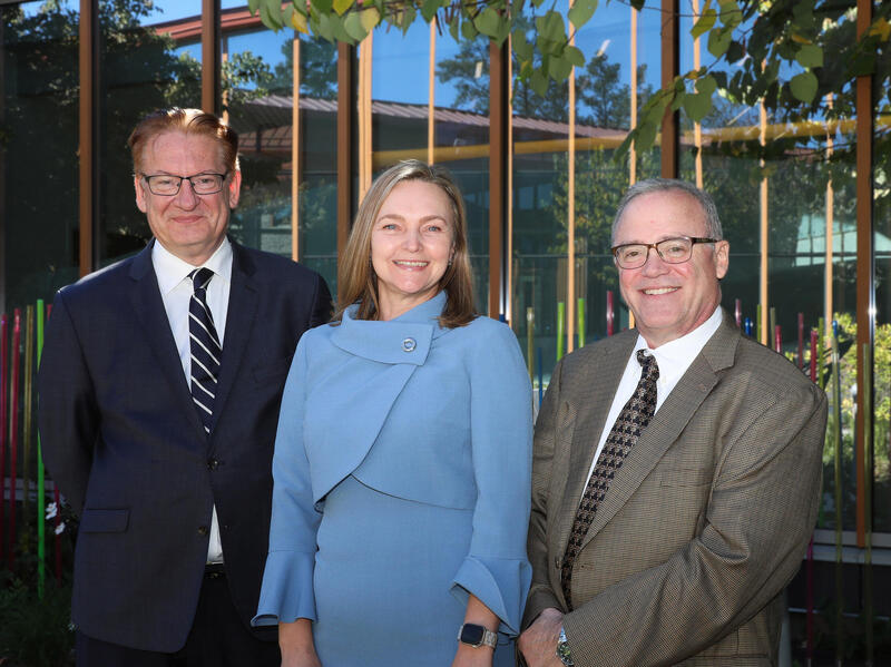 A group photo of two men standing on either side of a woman. 