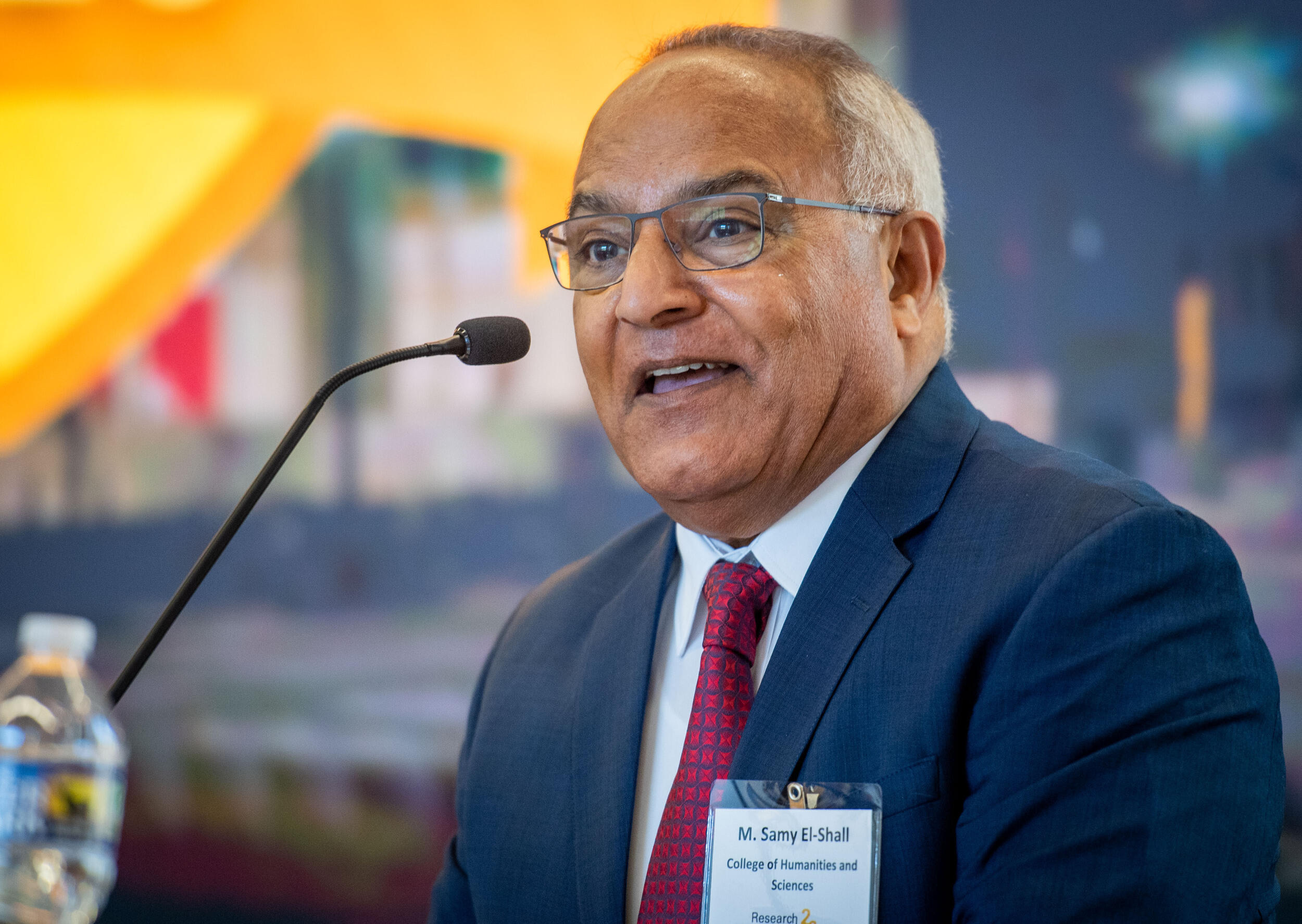 A photo of a mand speaking into a podium microphone. 