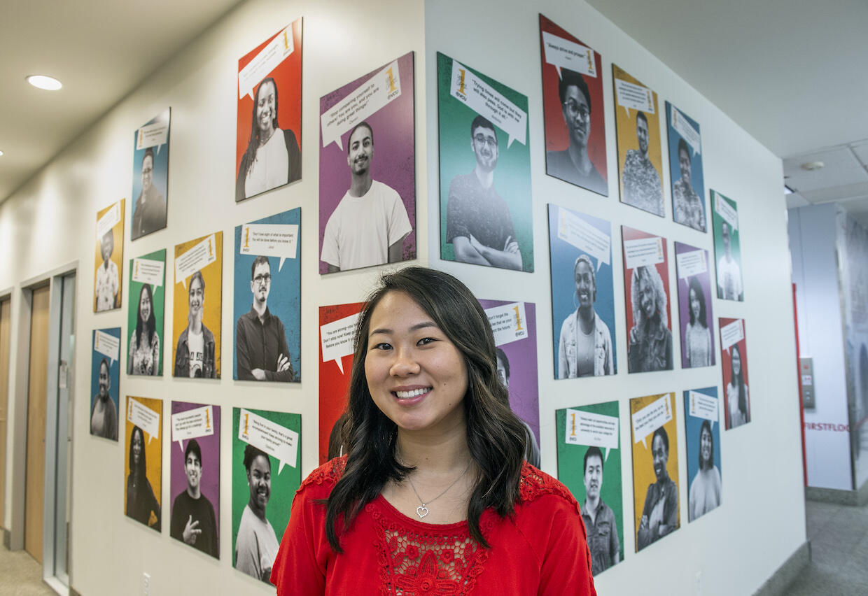 VCU student Amber Brown standing in front of a wall of portraits
