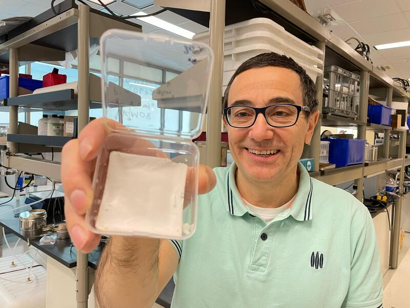 A photo of a man holding up a square clear container that has is white at the bottom. 