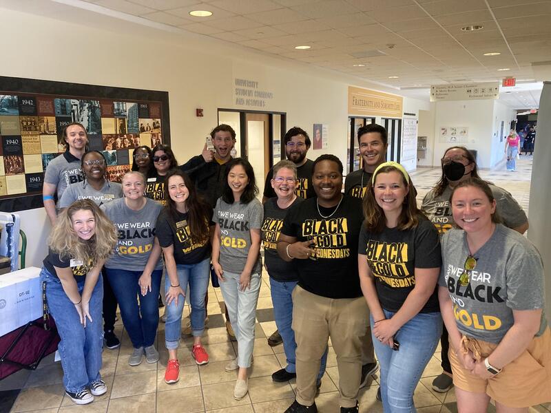 A group of 16 people standing in a hallway