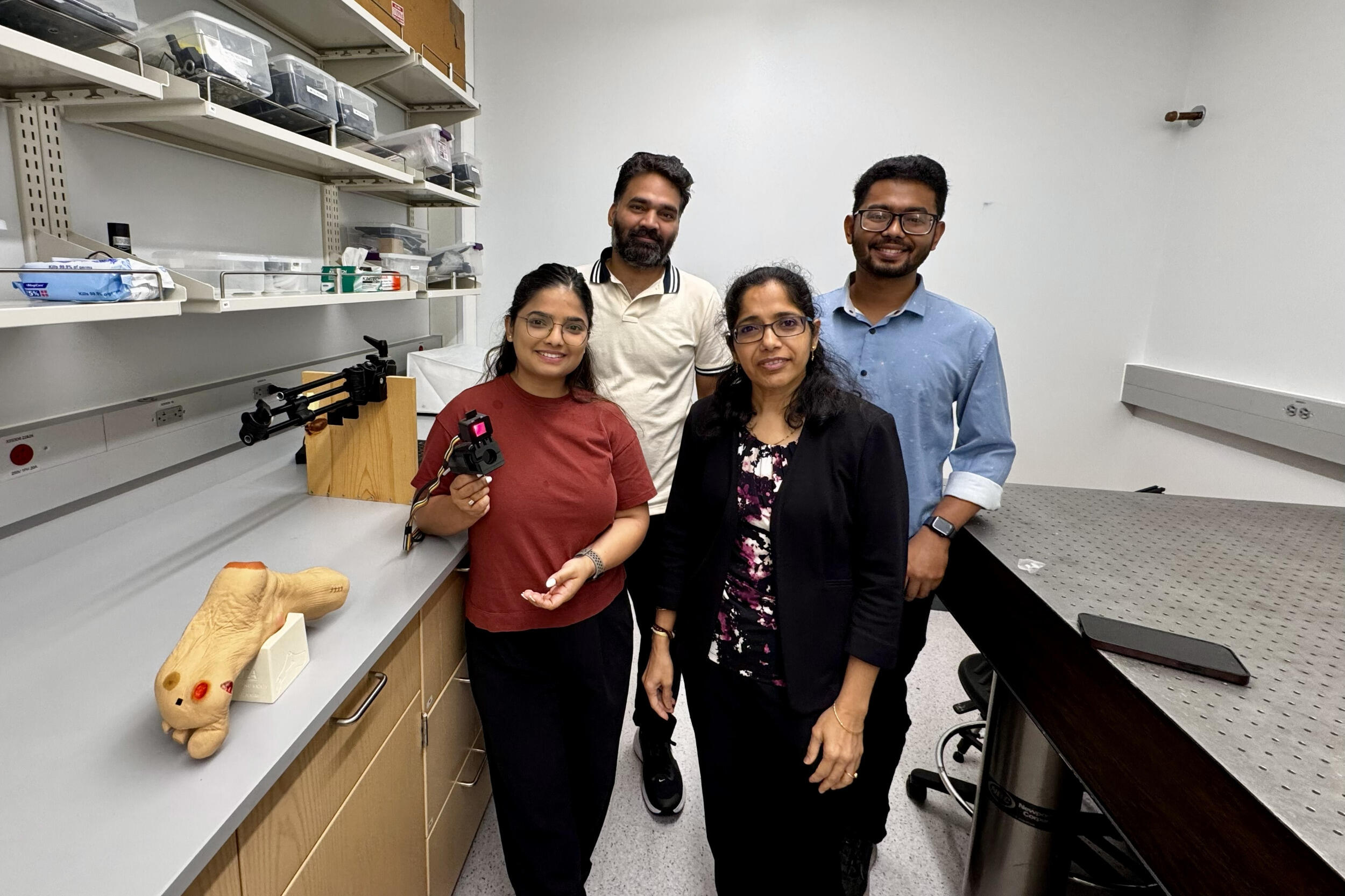Four people stand in a laboratory space.