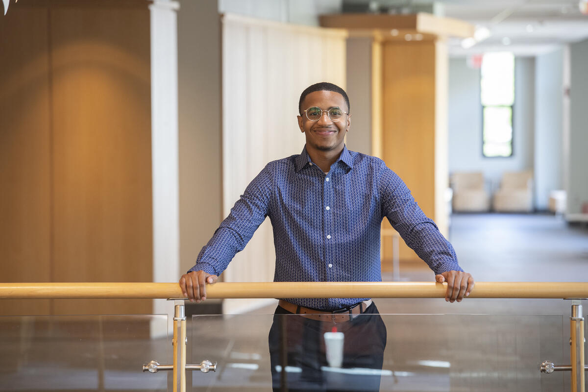 A man with his arms outstretched in front of him, resting on a railing