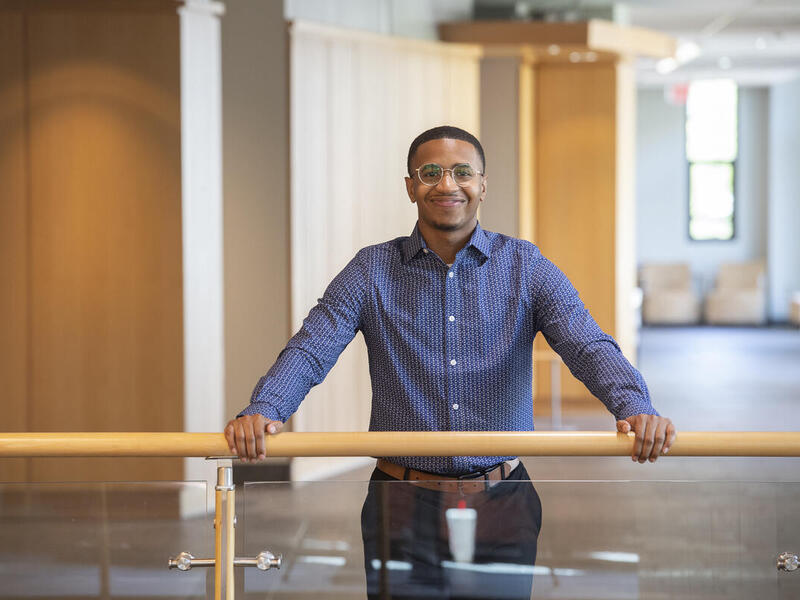 A man with his arms outstretched in front of him, resting on a railing