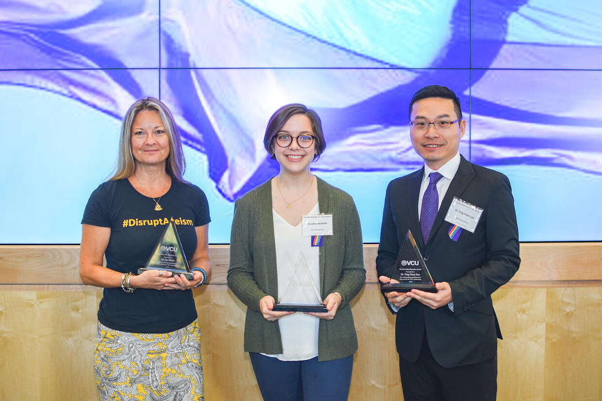 Three people holding awards.