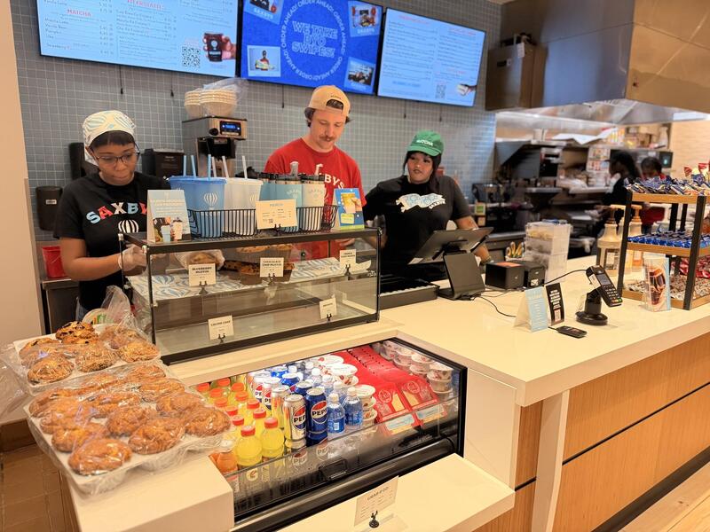 A photo of three people standing behind a coffee shop counter. 