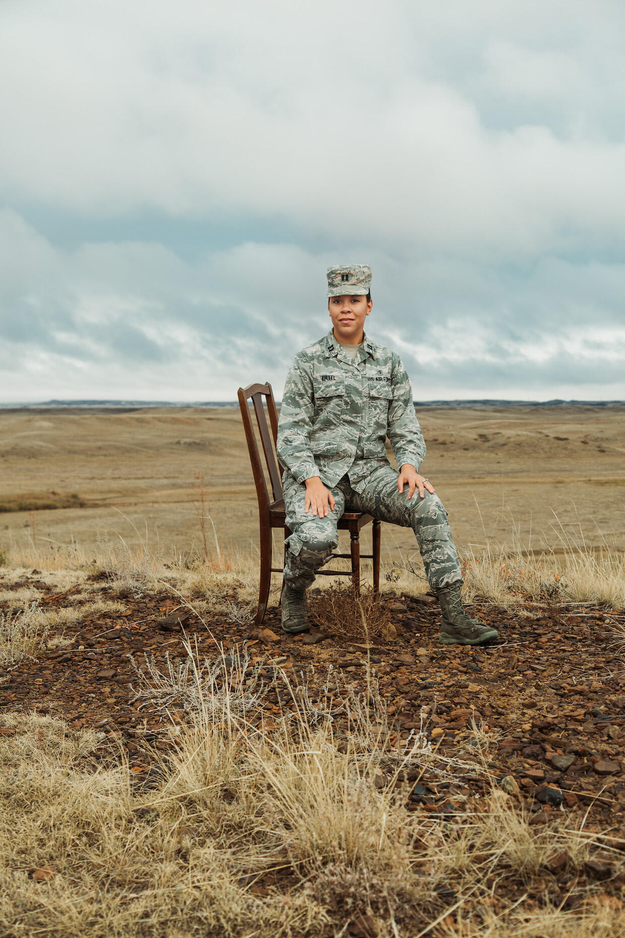 Woman in Army camo uniform seated in a field.