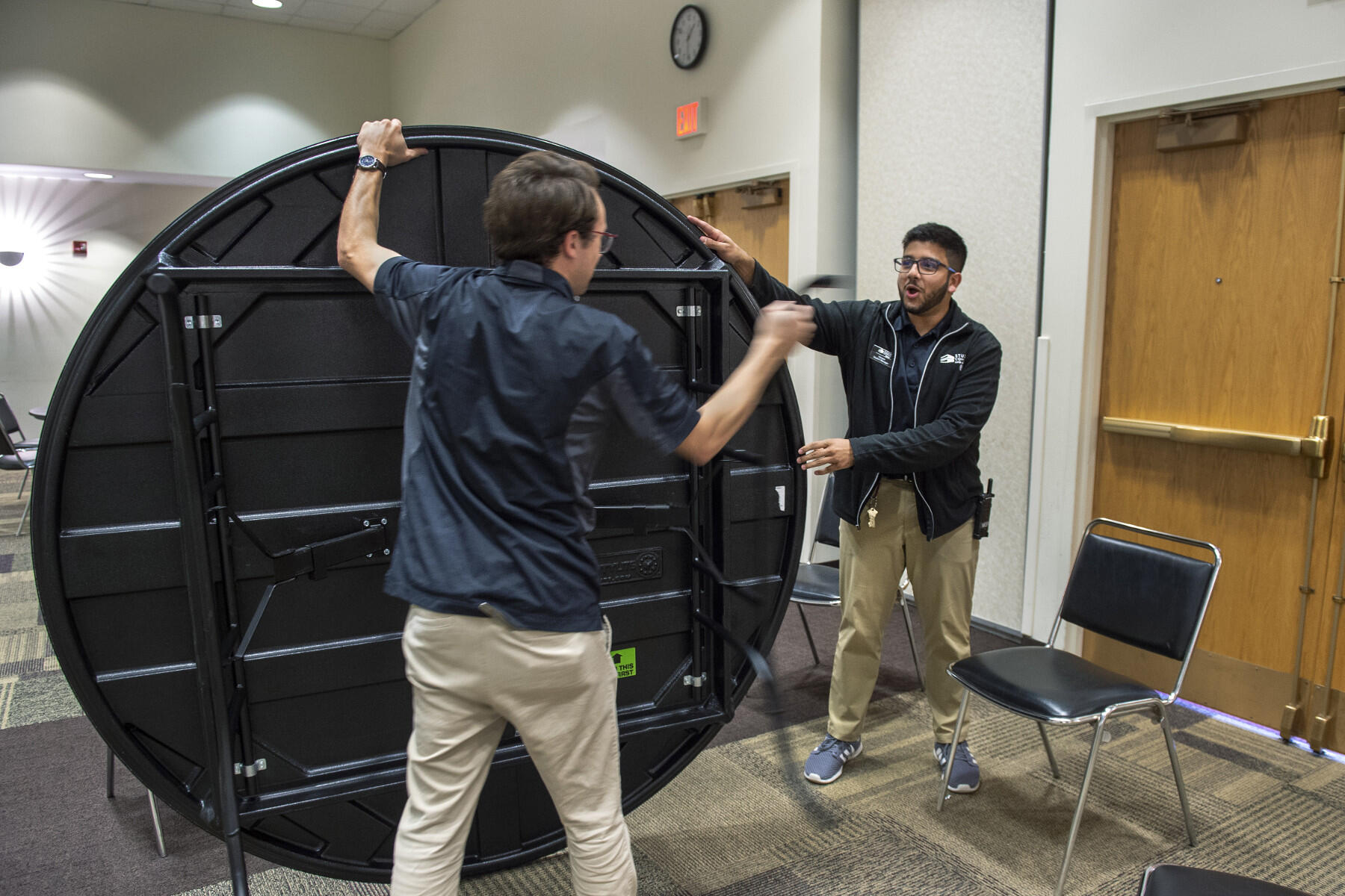 Two men set up a circular table.