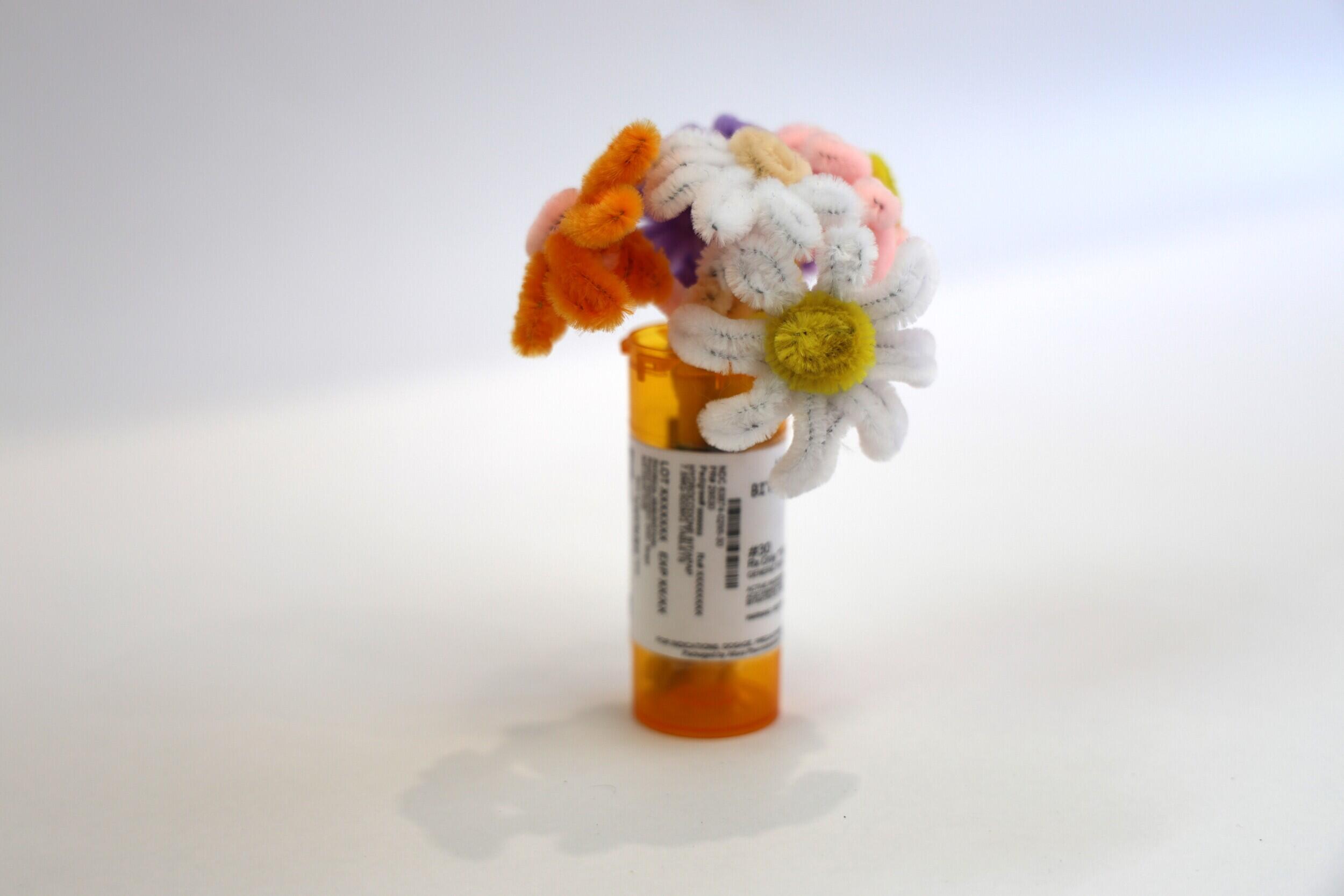 A photo of a pill bottle pipe cleaner flowers inside of it