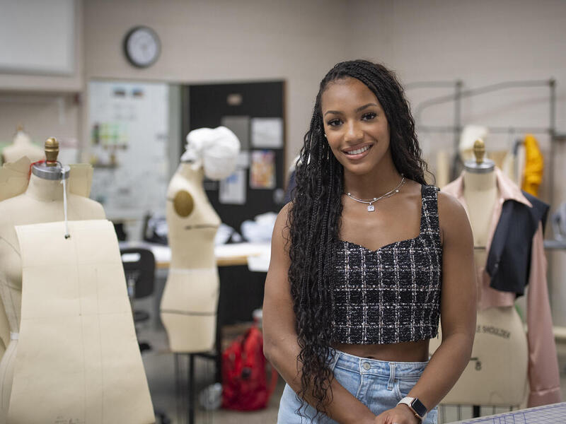 A woman standing in a room with dress forms. 