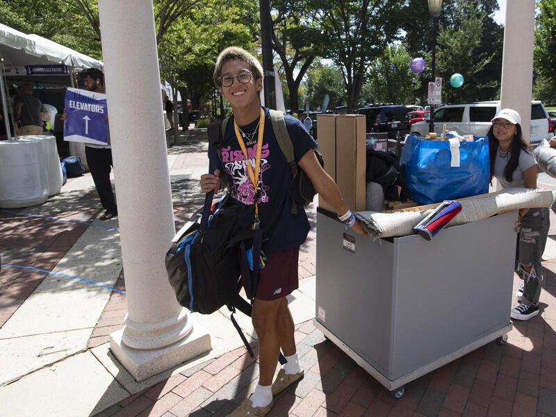 Two people wheel a large cart filled.