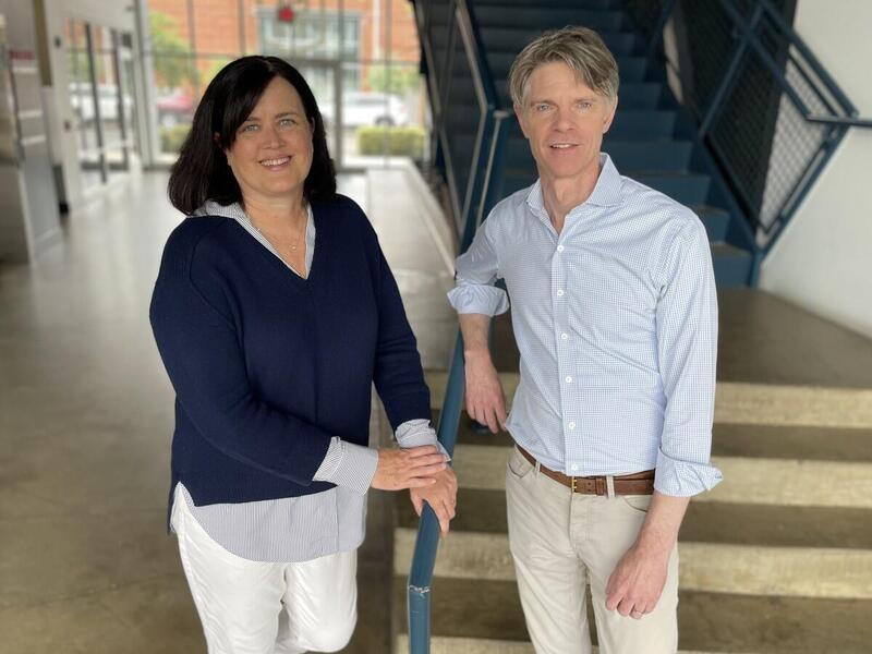 A photo of a woman and man standing in front of a staircase. 